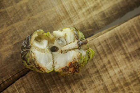 top view closeup picture of nice broken ripe sugar-apple with brown seed on wooden table backgroundの写真素材