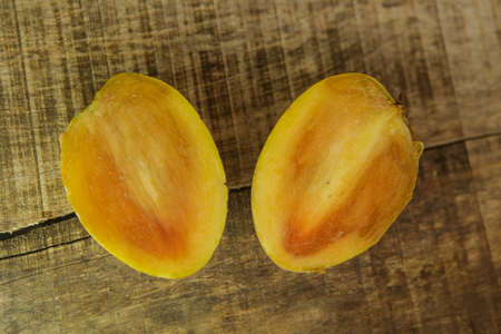 top view closeup cut into halves ripe yellow sapodilla on wooden table backgroundの写真素材