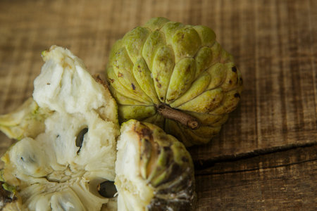 top view closeup picture of nice unbroken and broken ripe sugar-apples with brown seed on wooden...