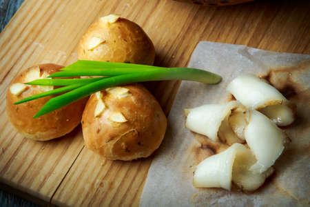 closeup traditional Ukrainian baked doughnut with garlic topping decorated with green onion and sliced tallow on wooden plateの写真素材