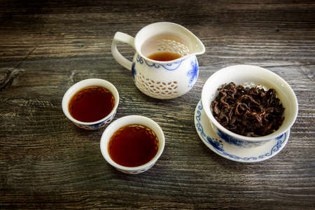 aroma black tea in traditional white chinese cups and teapot on wooden tableの写真素材