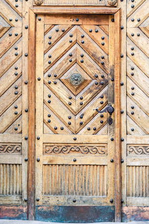closeup age-old light brown wooden fretwork door with metal decorationの写真素材