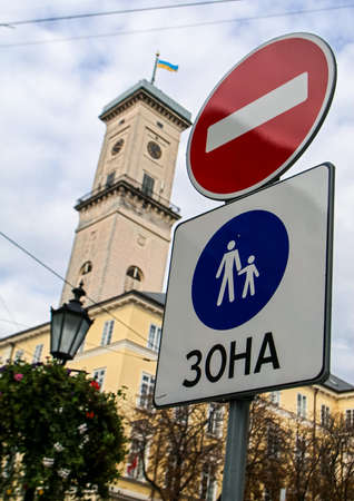 closeup road signs No Entry and Pedestrians Only against age-old clock tower and street lamp with flower bed in old european cityの写真素材