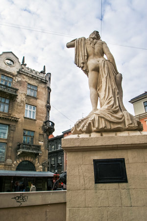 closeup backside view ancient statue of half naked woman against age-old building in old european cityの写真素材