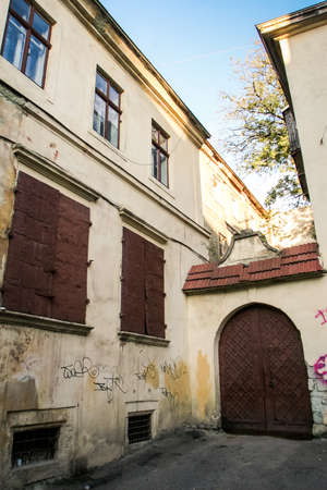 monastery yard with old iron door under roof with cross and building with old iron window shutters in european city Lvovの写真素材