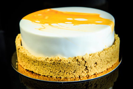 homemade musk cake musk cake coated with white and yellow glaze on black mirror background