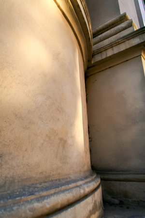 closeup part of yellow painted brick wall with iron-barred window of age-old Cathedral in european...