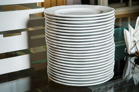 stack of empty white round plates on glass table on catering service banquetの写真素材