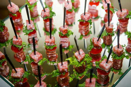 closeup ham snack on black  skewers served on glass plateau in catering service