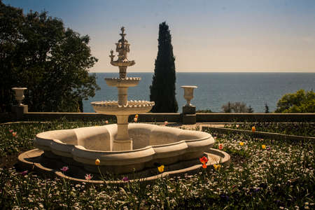 three level fountain among flowers in park of Vorontsov palace against azure sea cypress in Crimea Ukraine in springのeditorial素材