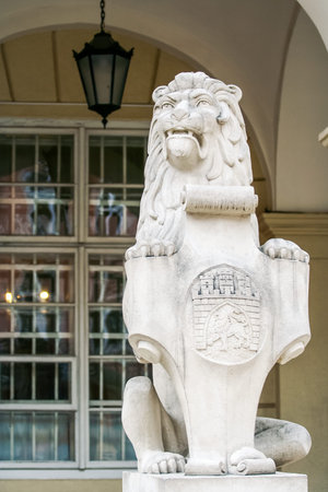closeup stone sculpture of sitting lion with city of Lvov armorial bearings against restaurant glass...