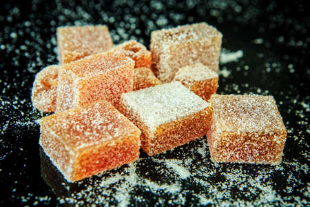 scattered tasty orange marmalade coated with sugar on black mirror background from aboveの写真素材