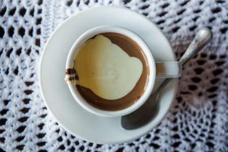 top view of white cup of hot white and milk chocolate served on white small plate with spoonの写真素材