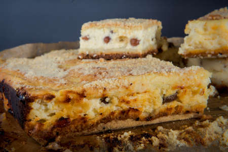 sliced tasty handmade cheesecake with raisins served on wooden tablet against gray backgroundの写真素材