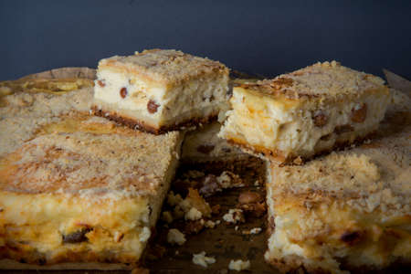 sliced delicious handmade cheesecake with raisins served on wooden tablet against gray backgroundの写真素材