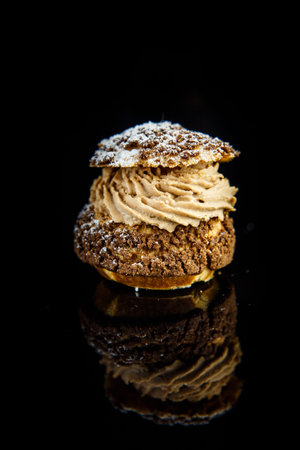 vertical view on french dessert shoo with caramel cream filling served on black mirror background...