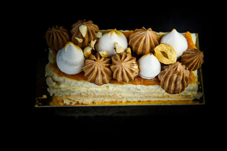 top view on piece of double layer Kiev cake abundantly decorated with chocolate cream and nuts closeup on black mirror background with reflectionの写真素材