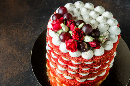 beautiful multi-layer cake with white airy bizet, red grapes and red and white rosesの写真素材
