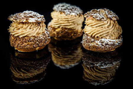 closeup three french dessert shoo with caramel cream filling served on black mirror background with reflectionの写真素材