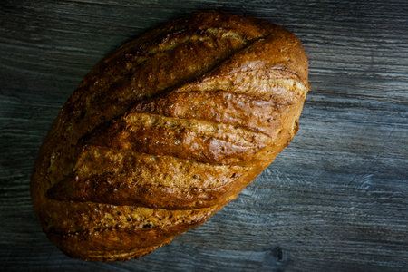 top view  of homemade oblong wheaten bread covered with honey lie on dark table background