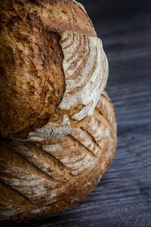two delicious whole homemade round white wheat bread lie on  dark wooden tableの写真素材