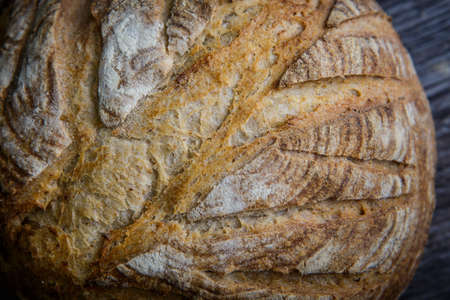 macro of whole handmade round white wheat bread lie on  dark wooden tableの写真素材