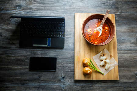top view of wooden table with traditional ukrainian food on wood tray next to laptop and smartphoneの写真素材