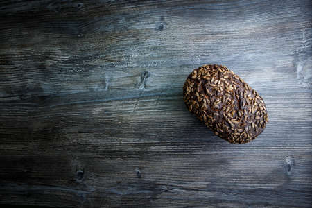 top view of whole tasty handmade rectangular rye bread with sunflower seeds on top lie on dark wooden backgroundの写真素材