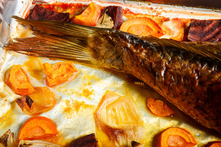 closeup roasted stuffed fish tail served with carrot, beetroot and onion pieces on metal try