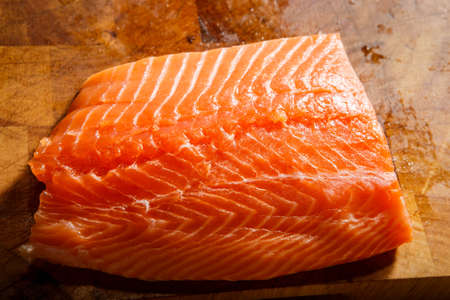big piece of raw salmon fillet with skin lie on wooden tabletの写真素材