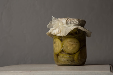 one small standard glass jar with homemade canned sliced zucchini decorated with handmade lid stand...