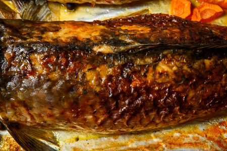 macro  top view on grilled whole stuffed fish with carrots, beetroot and onion pieces served on...