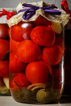 closeup glass jar with homemade canned tomatoes stand on kitchen table against two other glass jars