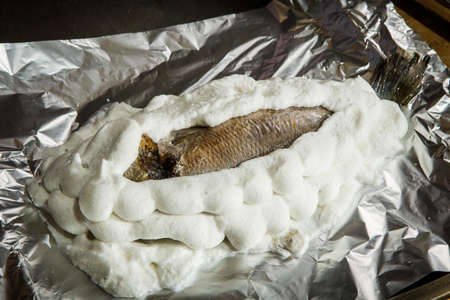 dorado covered with whipped egg whites with salt on foilの写真素材