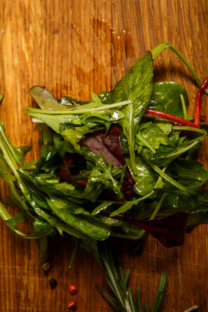 different types of green salad leaves lie on brown wooden background
