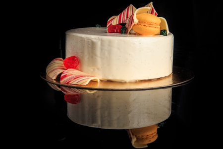 tasty round cake with white glaze decorated with yellow macaroon, colored chocolate and marmalade...