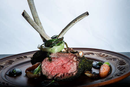 closeup big pieces of juicy rare grilled ribs meat steak served with sauce and grilled carrot against white backgroundの写真素材
