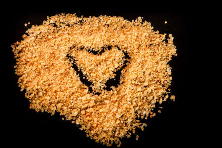 heart painted on big yellow natural organic sea salt poured on black mirror backgroundの写真素材