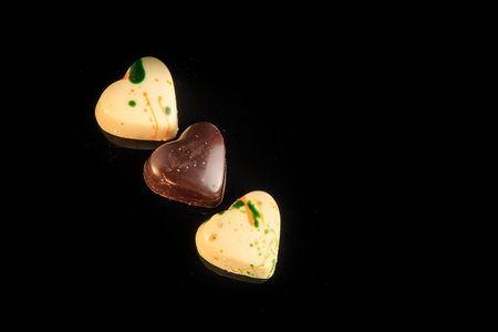top view on row made from heart-shaped white and black chocolate candies with colorful decoration on...