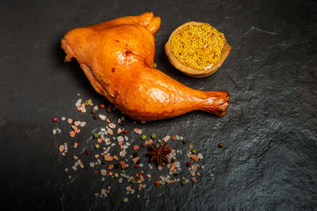 top view of smoked chicken leg with spices and fresh mustard in grain served on black backgroundの写真素材