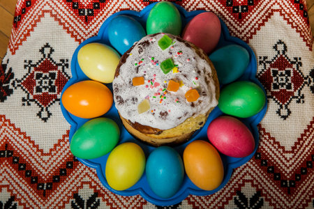 top view of decorated easter bread and coloful dyed easter eggs served on traditional embroidered...