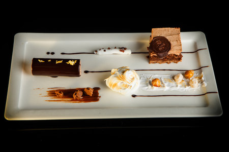 Top view of delicious chocolate and white cream mousse dessert served on rectangle plate on black...