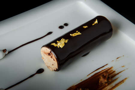 Top view of caramel creamy mousse with chocolate icing served on grey restaurant plate on black backgroundの写真素材