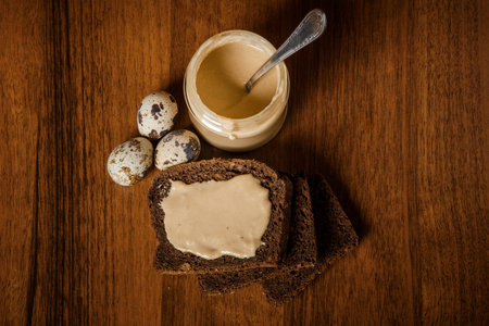 top view on jar with delicious tahini sesame seeds butter with spoon served with quail eggs and rye...