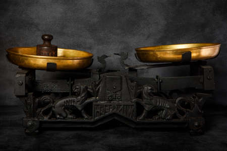 antiquarian weighing scales with two golden bowls and small black vintage weight on black backgroundの写真素材