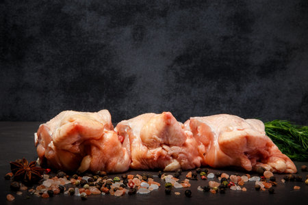 fresh parts of raw chicken served with pink salt, assorted spices and green dill on black background