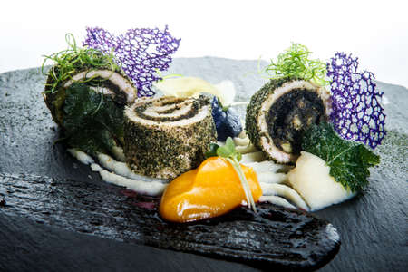 closeup modern decorated fish rolls stuffed with herbs served with delicious garnish against white backgroundの写真素材