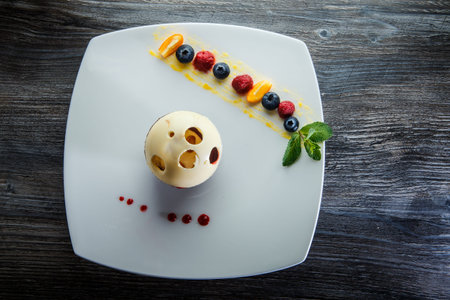top view on delicious white and black chocolate ball dessert served with assorted berries on white...