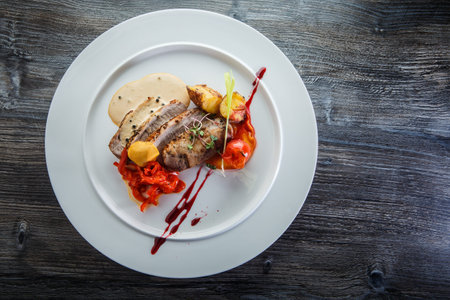 top view of baked meat pieces with grilled potato, tomato, pepper, and different sauces on white...