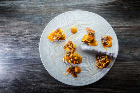 top view on exquisite restaurant dessert of crushed cupcakes with sweet sauce and caramelized pumpkin seeds on white plate on wooden tableの写真素材
